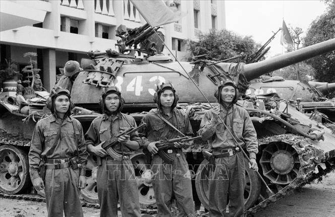 Trong chiến dịch Hồ Chí Minh, Bộ đội Tăng-Thiết giáp tham với quy mô lớn nhất. 11 giờ 30 phút ngày 30/4/1975, 2 chiếc xe tăng mang số hiệu 843 và 390 của Lữ đoàn tăng – thiết giáp 203, Quân đoàn 2 dẫn đầu đội hình, húc tung cánh cổng sắt tiến thẳng vào Dinh Tổng thống Ngụy quyền Sài Gòn. Trong ảnh: Trung úy Bùi Quang Thận, Đại đội trưởng xe tăng 4 (cầm cờ) cùng 3 chiến sĩ của Lữ đoàn Tăng – Thiết giáp 203, Sư đoàn 304, Quân đoàn 2 là những người đã tiến vào cắm cờ trên nóc Phủ Tổng thống Ngụy quyền Sài Gòn, trưa 30/4/1975. Ảnh: Vũ Tạo – TTXVN