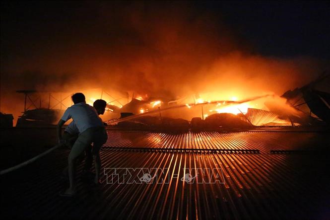 Trong ảnh: Người dân lên mái xưởng, tham gia dập lửa trong đám cháy cực lớn tại khu xưởng đèn led và thiết bị chiếu sáng của Công ty Bóng đèn phích nước Rạng Đông (đường Hạ Đình, quận Thanh Xuân, Hà Nội) . Ảnh: Thành Đạt - TTXVN