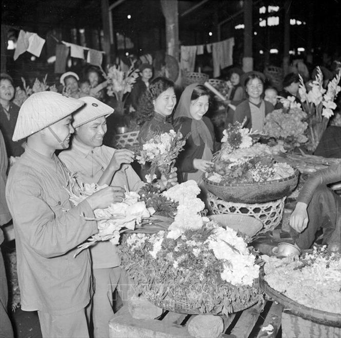Trong ảnh: Bộ đội và phụ nữ Thủ đô vui tươi đi mua sắm hoa Tết Bính Thân, năm 1956. Ảnh: TTXVN  