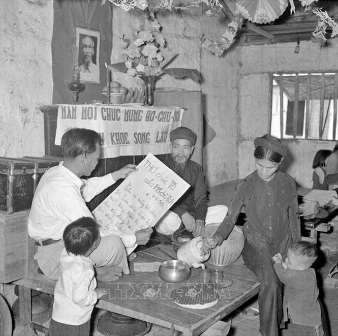 Trong ảnh: Sáng mồng 1 Tết Bính Thân 1956, cả gia đình ngồi trước bàn thờ Tổ quốc nghe đọc thư chúc Tết của Bác Hồ. Ảnh: TTXVN  