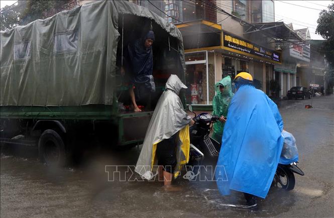 Trong ảnh: Lực lượng cứu hộ giúp người dân thành phố Hà Tĩnh di chuyển phương tiện giao thông lên chỗ cao. Ảnh: Công Tường-TTXVN