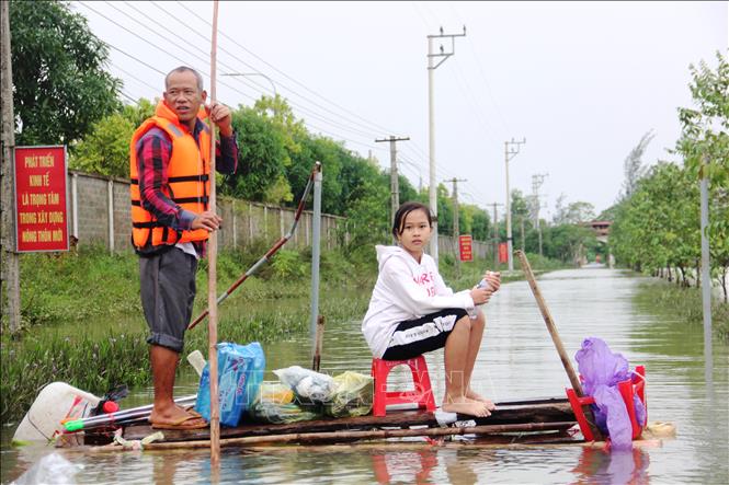 Hai cha con ở thôn Bình Tiến (xã Tân Lâm Hương, huyện Thạch Hà) dùng bè chuối ra để nhận hàng cứu trợ. Ảnh: Hoàng Ngà - TTXVN