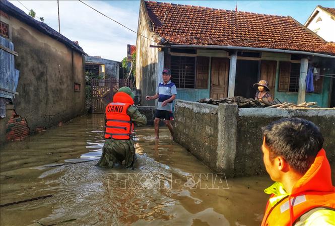 Trong ảnh: Lực lượng công an huyện Lệ Thủy lội nước, đưa hàng cứu trợ đến những gia đình bị cô lập trong nước lũ. Ảnh: Thành Đạt - TTXVN