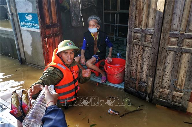 Trong ảnh: Lực lượng công an huyện Lệ Thủy lội nước, đưa hàng cứu trợ đến những gia đình bị cô lập trong nước lũ. Ảnh: Thành Đạt - TTXVN