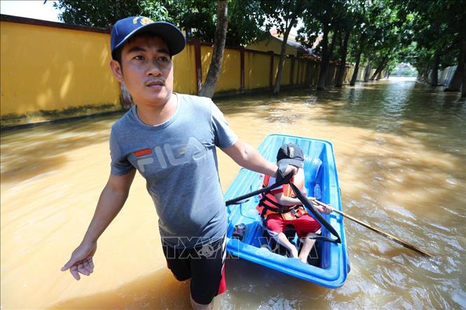 Trong ảnh: Nước rút dần, người dân rời nhà để tìm thực phẩm, nước uống. Ảnh: Thành Đạt - TTXVN
