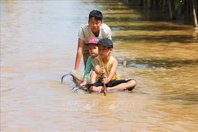 Trong ảnh: Trẻ em đẩy bè đi lấy hàng cứu trợ. Ảnh: Thành Đạt - TTXVN