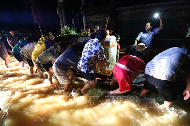 Trong ảnh: Người nhà vất vả di chuyển linh cữu trong đêm, xung quanh là nước lũ. Ảnh: Thành Đạt - TTXVN
