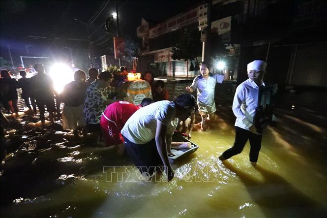 Trong ảnh: Hình ảnh éo le đám tang phải di chuyển trong đêm, xung quanh là nước lũ. Ảnh: Thành Đạt - TTXVN
