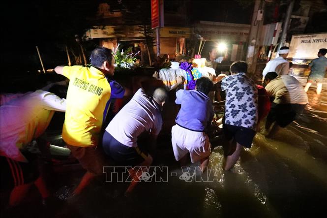 Trong ảnh: Người nhà vất vả di chuyển linh cữu trong đêm xung quanh là nước lũ. Ảnh: Thành Đạt - TTXVN
