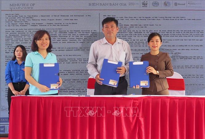 Đại diện WWF (ngoài cùng bên trái) trao biên bản hỗ trợ làm sạch môi trường biển Hòn Yến cho chính quyền địa phương. Ảnh: Xuân Triệu - TTXVN                               