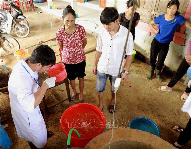 Trong ảnh: Nhân viên Trung tâm Y tế dự phòng huyện Lệ Thủy hướng dẫn người dân khử khuẩn nước sinh hoạt bằng dung dịch Cloramin B cho hộ Lê Thị Đào ở thôn Mai Thúy, xã Mai Thủy. Ảnh: Vũ Sinh - TTXVN
