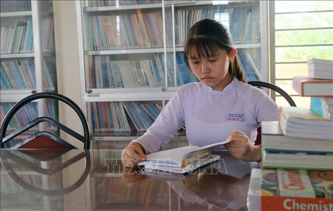 Trong ảnh: Em Đặng Minh Thư luôn tranh thủ trời gian rảnh lên thư viện trường để đọc thêm tài liệu. Ảnh: Công Mạo-TTXVN