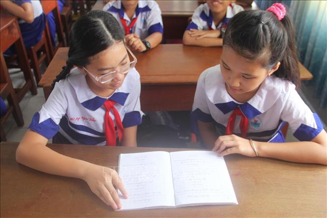 Trong ảnh: Em Võ Ngọc Gia Bảo (bên trái) trao đổi bài học với bạn cùng lớp. Ảnh: Hữu Chí-TTXVN