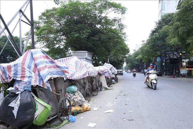 Trong khi chờ cơ quan chức năng xử lý vấn đề, Công ty TNHH một thành viên Môi trường đô thị Hà Nội (URENCO) chỉ đạo các đơn vị trực thuộc chủ động tập kết xe gom về điểm lưu chứa tạm thời, phủ bạt, phun thuốc khử khuẩn bảo đảm vệ sinh. Trong ảnh: Xe chở rác xếp dọc đường Kim Ngưu, quận Hai Bà Trưng (ảnh chụp lúc 13h ngày 25/10/2020). Ảnh: Hoàng Hiếu - TTXVN 
