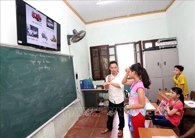 Trong ảnh: Giáo viên Nguyễn Đức Hạnh, 28 tuổi, 5 năm công tác (trước là học sinh khuyết tật đã điều trị, học tập tại Trung tâm, thi đỗ Đại học và được Trung tâm cho (chi phí ăn học) học đại học khoa Giáo dục đặc biệt - Trường ĐH Sư phạm Hà Nội và được Trung tâm tuyển dụng là viên chức giáo viên) đang dạy văn hóa cho học sinh khiếm thính (điếc câm). Ảnh: Anh Tuấn – TTXVN