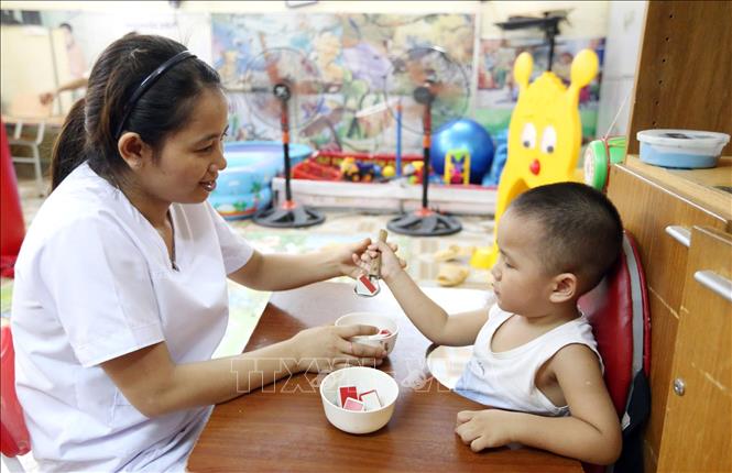Trong ảnh: Kỹ thuật viên PHCN, điều dưỡng Nguyễn Thị Mơ, 34 tuổi, 11 năm công tác đang dạy kỹ năng sống cho trẻ em khuyết tật (hoạt động trị liệu), (Bằng khen của Bộ LĐTBXH năm 2017,2020). Ảnh: Anh Tuấn – TTXVN