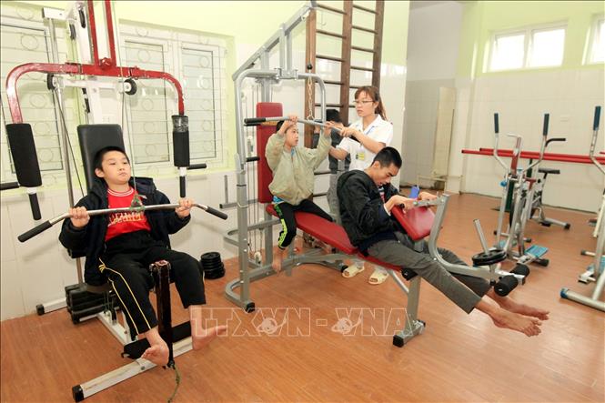 Trong ảnh: Kỹ thuật viên PHCN, điều dưỡng Nguyễn Hằng Nga, 28 tuổi, 7 năm công tác đang hướng dẫn trẻ em khuyết tật tập luyện PHCN. Ảnh: Anh Tuấn – TTXVN
