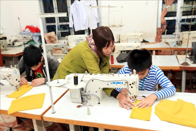 Trong ảnh: Giáo viên dạy nghề Phan Thị Yến, 37 tuổi, 10 năm công tác đang dạy nghề may cho học sinh khuyết tật (khiếm thính). Ảnh: Anh Tuấn – TTXVN