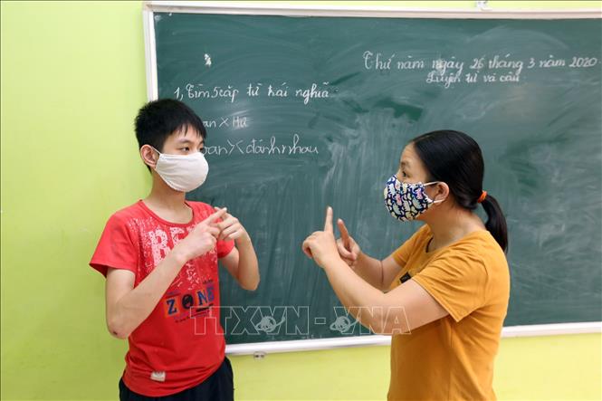 Trong ảnh: Đảng viên Khuất Thị Mai Anh 41 tuổi, 11 năm công tác, Phó trưởng khoa Giáo dục đặc biệt đang dạy ngôn ngữ ký hiệu và dạy văn hóa cho học sinh khiếm thính trong giai đoạn dịch COVID-19, (chị đã 3 lần được Bằng khen của Bộ LĐTBXH vào những năm 2014, 2017, 2020). Ảnh: Anh Tuấn – TTXVN