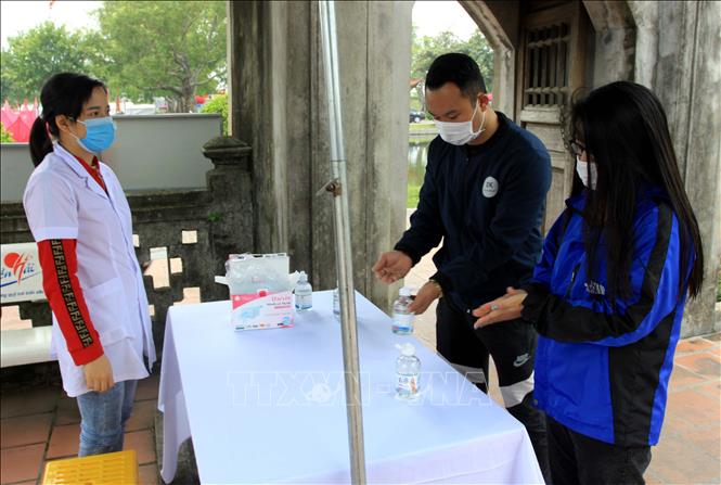 Trong ảnh: Du khách được nhắc nhở sát khuẩn tay, đeo khẩu trang trước khi vào chùa. Ảnh: Thế Duyệt – TTXVN 