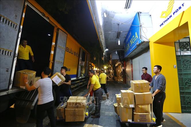 Trong ảnh: Nhân viên Công ty Phát hành báo chí Trung ương (thuộc Vietnam Post) bốc xếp hàng cứu trợ lên xe để vận chuyển vào miền Trung (ảnh chụp đêm 26/10/2020). Ảnh: Minh Quyết - TTXVN