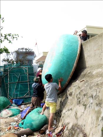 Trong ảnh: Người dân di dời thuyền thúng đến vị trí an toàn tránh bão. Ảnh: Lê Ngọc Phước- TTXVN
