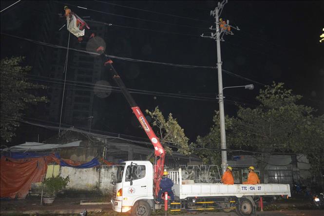 Công nhân Công ty Điện lực Bình Định làm việc thâu đêm để khắc phục sự cố tôn bay làm đứt đường dây điện cao áp 22kV trên đường Hoàng Văn Thụ, thành phố Quy Nhơn. Ảnh: Phạm Kha – TTXVN