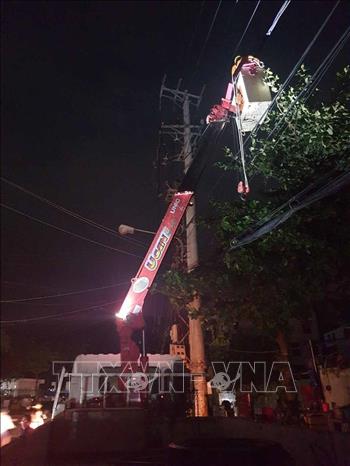 Công nhân Công ty Điện lực Bình Định làm việc thâu đêm để khắc phục sự cố tôn bay làm đứt đường dây điện cao áp 22kV trên đường Hoàng Văn Thụ, thành phố Quy Nhơn. Ảnh: Phạm Kha – TTXVN