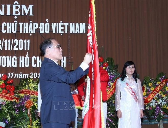 Trong ảnh: Chủ tịch Quốc hội Nguyễn Sinh Hùng gắn Huân chương Hồ Chí Minh lên lá cờ truyền thống của Hội Chữ thập Đỏ Việt Nam tại Lễ kỷ niệm 65 năm Ngày thành lập Hội (20/11/2011). Ảnh: Nhan Sáng-TTXVN