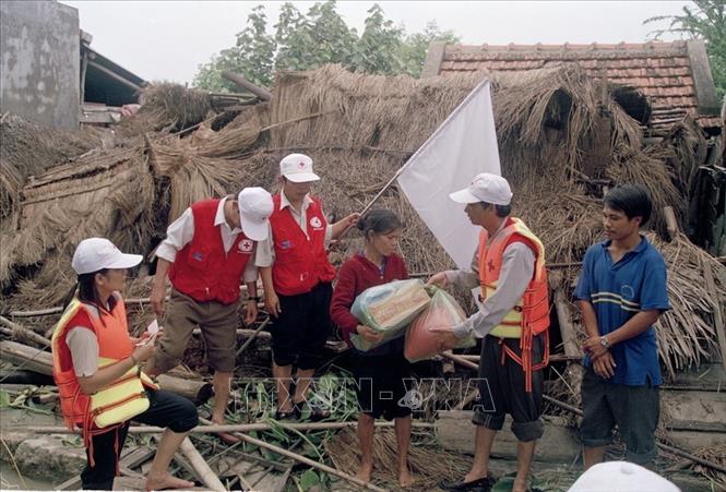 Trong ảnh: Đại diện chính quyền và Hội Chữ thập đỏ tỉnh Bình Định đến thăm, tặng quà gia đình bà Lê Hưởng (63 tuổi) ở thôn Đông Điền, Phước Thắng (Tuy Phước) bị sập nhà hoàn toàn trong đợt mưa lũ (2003). Ảnh: Phạm Biết - TTXVN