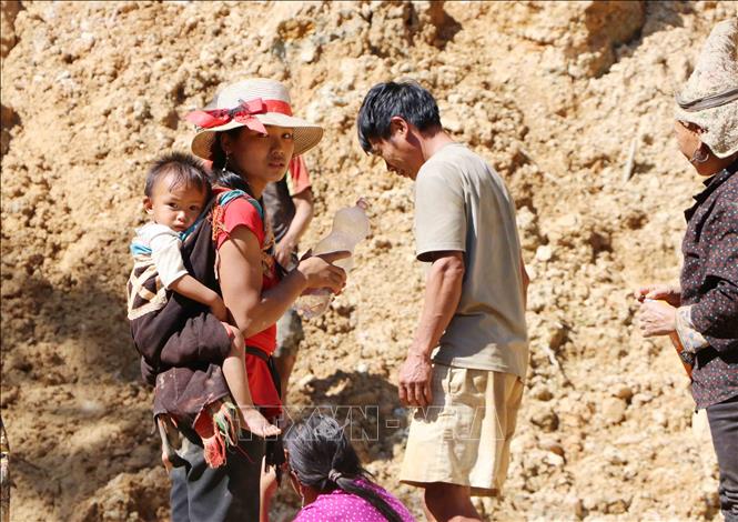 Chị Tẩn Tả Mẩy, 23 tuổi, người dân tộc Dao, xã Hua Bum cõng con gái Phàn Thị Thư mới hơn 1 tuổi đi khai thác vàng. Ảnh: Hoàng Thùy Oanh-TTXVN