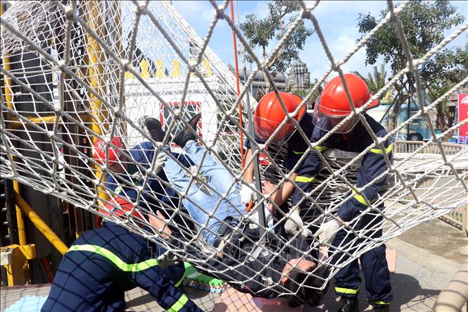 Trong ảnh: Diễn tập giải cứu đưa người bị kẹt trên trò chơi tháp rơi xuống đất an toàn bằng cách đu dây. Ảnh: Trần Lê Lâm - TTXVN 