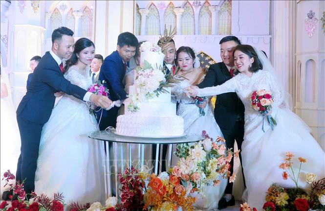 Các cặp đôi thực hiện nghi lễ cắt bánh ga tô tai Lễ cưới tập thể. Ảnh: Thu Hằng-TTXVN