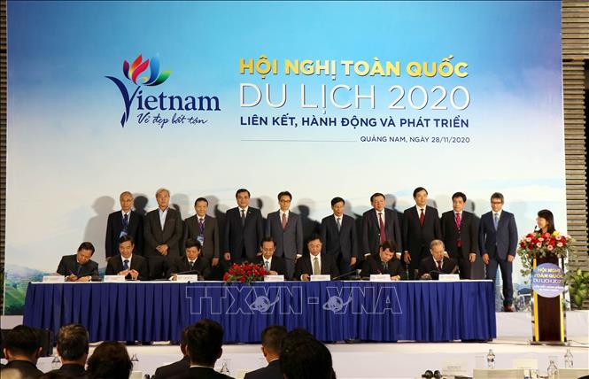Photo: A signing ceremony for cooperation agreements to boost tourism development between Hanoi and Ho Chi Minh City and five localities in the central key economic region. VNA Photo: Trần Tĩnh