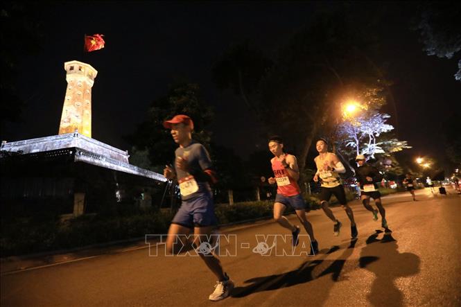 Trong ảnh: Các vận động viên chạy qua cột cờ Hà Nội trên đường Điện Biên Phủ. Ảnh: Thành Đạt - TTXVN
