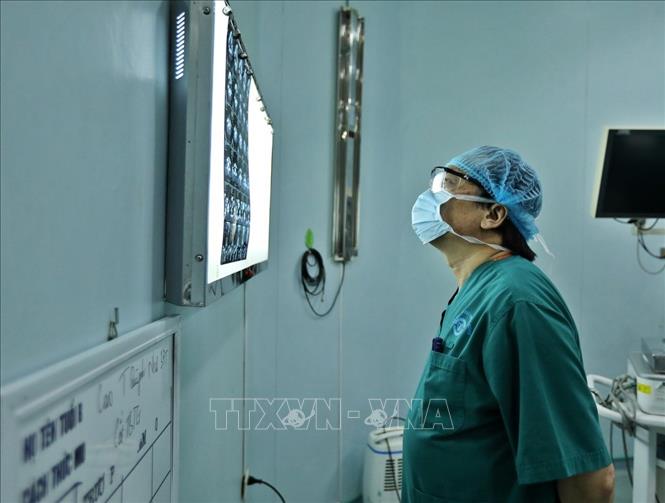 Trong ảnh: PGS. TS Trần Ngọc Lương đọc phim chụp của bệnh nhân trước khi phẫu thuật. Ảnh: Minh Quyết – TTXVN