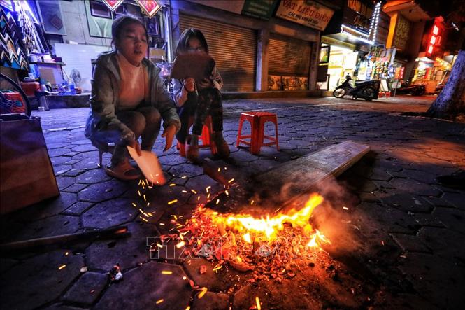 Trong ảnh: Các e nhỏ thích thú ngồi nhóm lửa sưởi ấm trên phố Nguyễn Thái Học. Ảnh: Thành Đạt - TTXVN 
