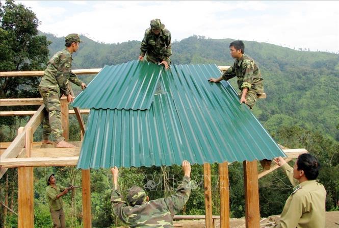 Trong ảnh: Cán bộ, chiến sỹ Bộ đội Biên phòng Lai Châu giúp dân dựng nhà, lập bản để định cư, ổn định cuộc sống. Ảnh: Công Tuyên-TTXVN