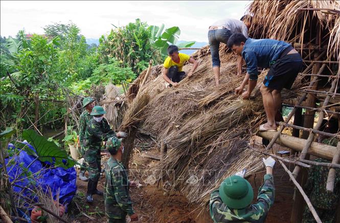 Trong ảnh: Cán bộ, chiến sĩ biên phòng tỉnh Điện Biên và người dân địa phương thực hiện tháo dỡ nhà ở tạm, dột nát, không đảm bảo an toàn để di chuyển người dân đến sinh sống ở những ngôi nhà mới khang trang đã bàn giao cho người dân. Ảnh: Xuân Tiến-TTXVN