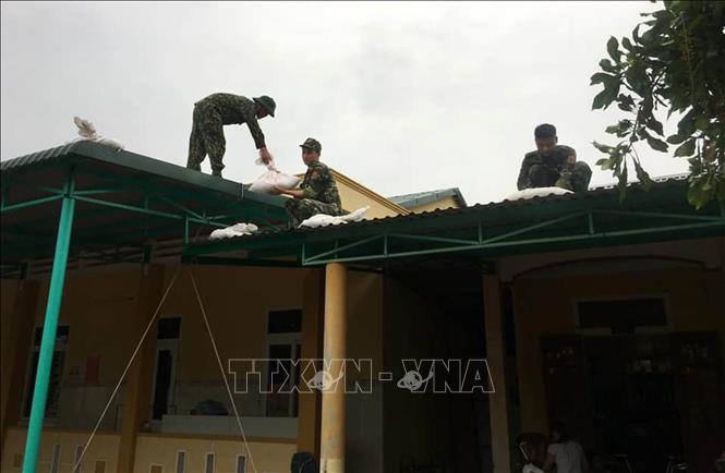 Trong ảnh: Bộ đội biên phòng Quảng Trị giúp người dân chằng chống nhà cửa chuẩn bị ứng phó với bão số 5. Ảnh: Hồ Cầu-TTXVN