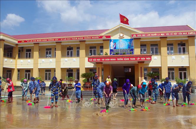 Trong ảnh: Cán bộ, chiến sĩ Hải đội 102 (Bộ Tư lệnh Vùng Cảnh sát biển 1) cùng các thầy, cô giáo trường Tiểu học Cồn Sẻ làm vệ sinh phòng học, sân trường do mưa lũ gây ra. Ảnh: TTXVN