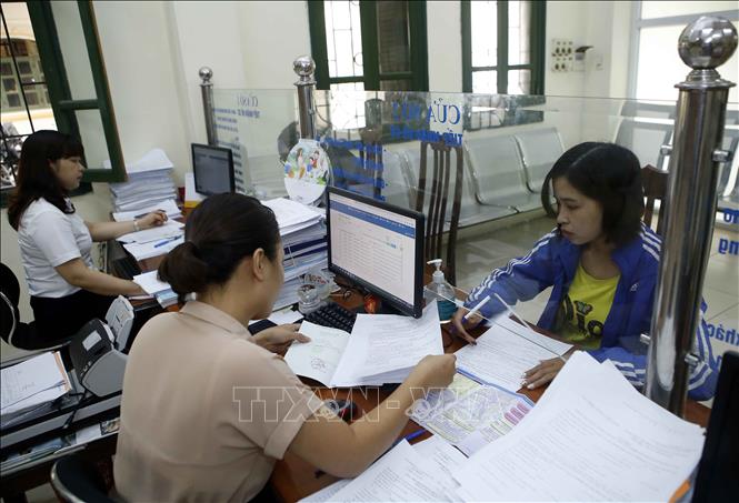 Trong ảnh: Nhân viên Bảo hiểm xã hội tỉnh Hưng Yên hướng dẫn người dân làm thủ tục tham gia Bảo hiểm xã hội. Ảnh: Phạm Kiên - TTXVN