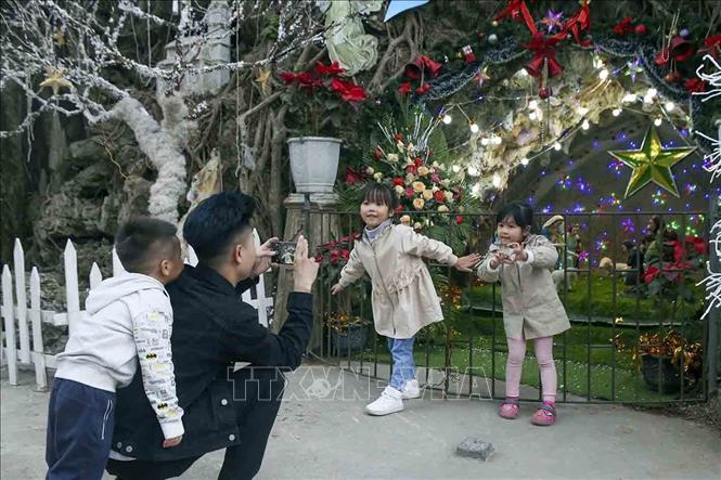 Trong ảnh: Trẻ em chụp ảnh kỷ niệm tại hang đá giáo xứ Sở Kiện. Ảnh: Tuấn Đức - TTXVN