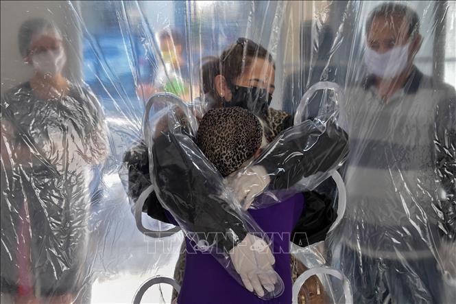 Trong ảnh: Một cô gái phải ôm mẹ của mình qua tấm màn ni lông khi tới thăm bà trong viện dưỡng lão ở Sao Paulo, Brazil, trong bối cảnh dịch COVID-19 hoành hành ngày 13/6/2020. Ảnh: AFP/TTXVN