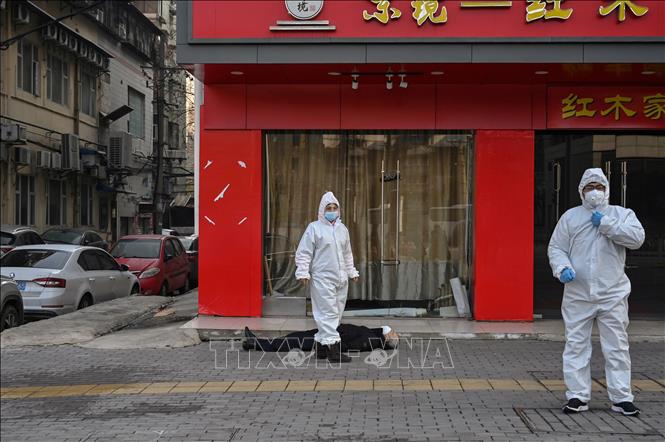 Trong ảnh: Lực lượng chức năng mặc trang phục bảo hộ kiểm tra tại hiện trường một người ngất xỉu và tử vong nghi do dịch COVID-19, trên tuyến phố ở Vũ Hán, Trung Quốc ngày 30/1/2020. Ảnh: AFP/TTXVN