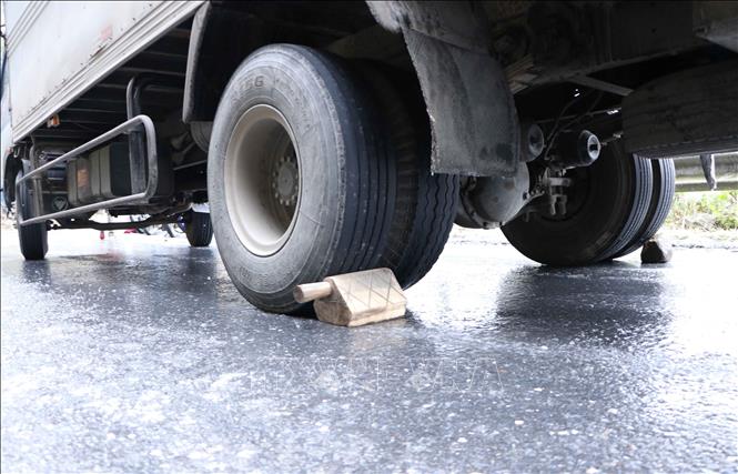 Trong ảnh: Các chủ xe phải chèn bánh để chống trượt. Ảnh: Nguyễn Oanh-TTXVN.