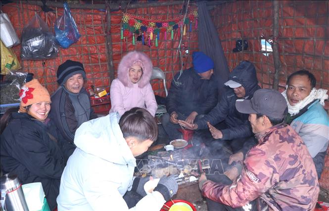 Trong ảnh: Bữa ăn vội ngay trên đèo khi chờ băng tan, xe mới có thể di chuyển được. Ảnh: Nguyễn Oanh-TTXVN.