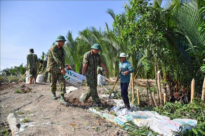 Trong ảnh: Bộ đội  giúp dân xã Hòa Chánh làm đường giao thông nông thôn. Ảnh: Lê Sen – TTXVN