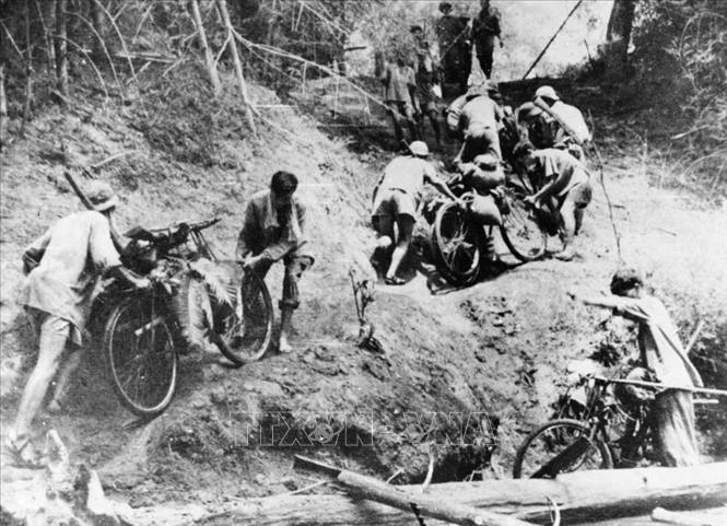 Ngày 19/5/1959, Thường trực Tổng Quân uỷ quyết định thành lập Đoàn 559, chính thức giao nhiệm vụ mở đường chi viện vào chiến trường miền Nam. Quyết định xây dựng tuyến đường Trường Sơn chiến lược và thực hiện thắng lợi quyết định ấy khẳng định sự nhạy bén trong tư duy và tài thao lược trong chỉ đạo chiến tranh của Đảng ta trong cuộc kháng chiến chống Mỹ, cứu nước. Trong ảnh: Giai đoạn đầu hoạt động trên con đường bí mật xuyên rừng rậm, núi cao, trên tuyến vận tải chiến lược này, quân ta đã vận chuyển thô sơ bằng gùi, xe thồ, nhỏ lẻ với cung ngắn. Ảnh: TTXVN