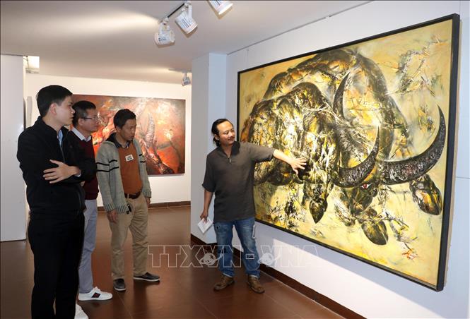 Trong ảnh: Họa sĩ Ngô Thanh Hùng giới thiệu về nét đẹp của con trâu trong văn hóa Việt qua tranh vẽ được trưng bày tại triển lãm. Ảnh: Trần Lê Lâm - TTXVN 